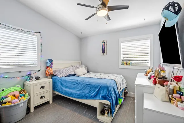 a bedroom with furniture a flat screen tv and a window