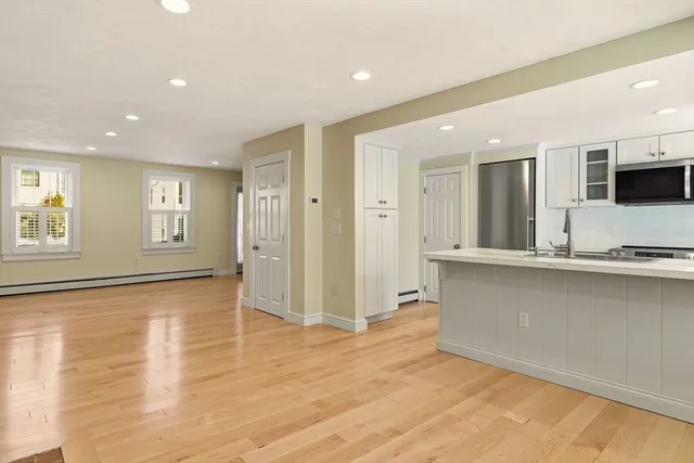 a view of an empty room with window and wooden floor