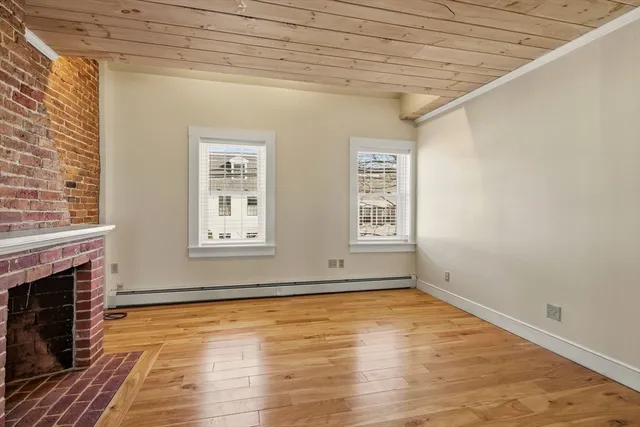 a view of empty room with wooden floor and fireplace