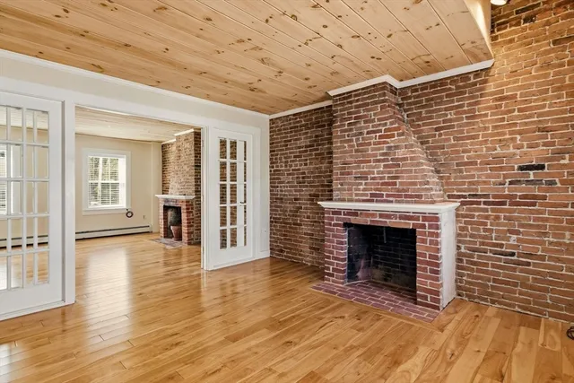a view of an empty room with wooden floor and a fireplace