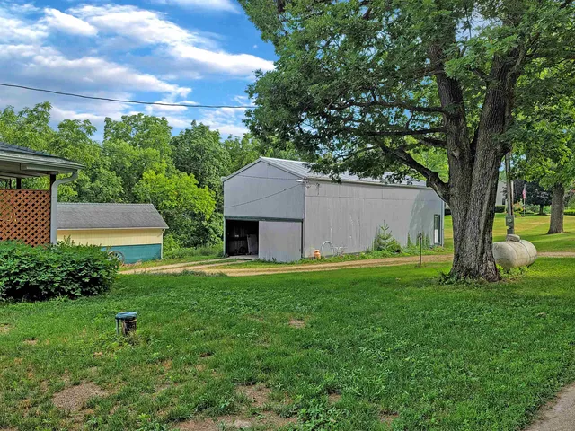 a backyard of a house with plants and large tree