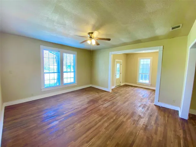 a view of an empty room with window and wooden floor
