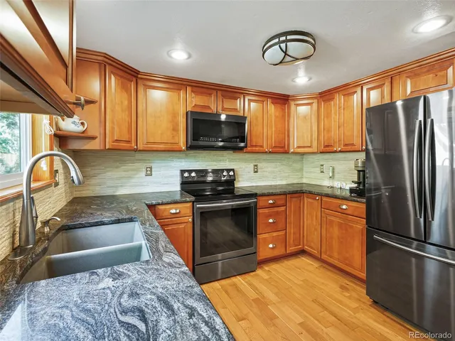 a kitchen with stainless steel appliances granite countertop a stove a sink dishwasher a refrigerator and a microwave