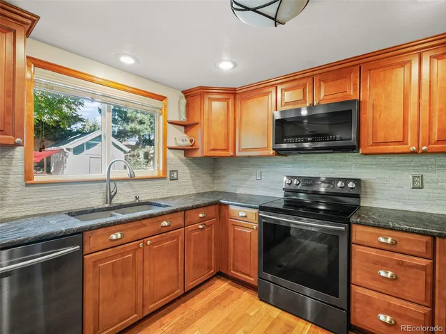 a kitchen with granite countertop a sink stove top oven and cabinets