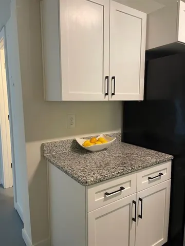 a kitchen with granite countertop white cabinets and a sink