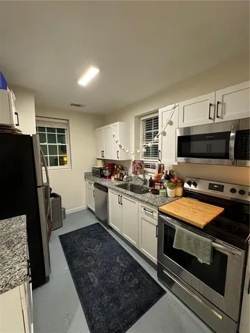 a kitchen with granite countertop a sink a counter top space stainless steel appliances and a window