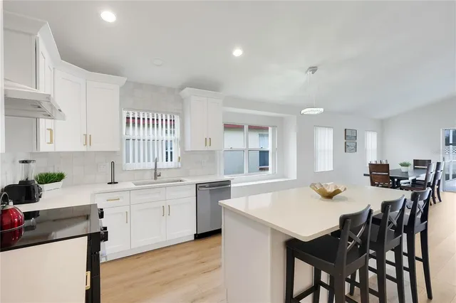 a kitchen with stainless steel appliances a table chairs refrigerator and wooden cabinets