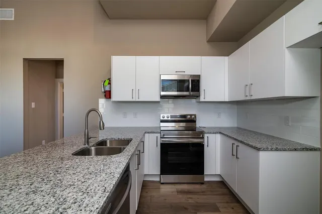 a kitchen with kitchen island granite countertop a sink cabinets and stainless steel appliances