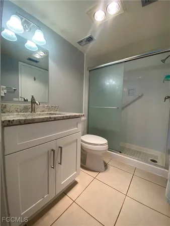 a bathroom with a granite countertop sink a toilet and a mirror