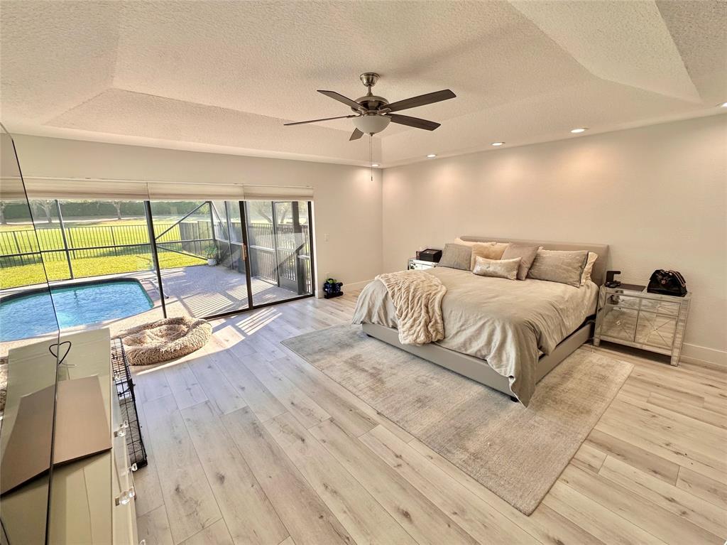 11392 Boca Woods Lane Boca Raton, FL 33428 - Photo 12 of 26 a bedroom with a bed a ceiling fan and a large window