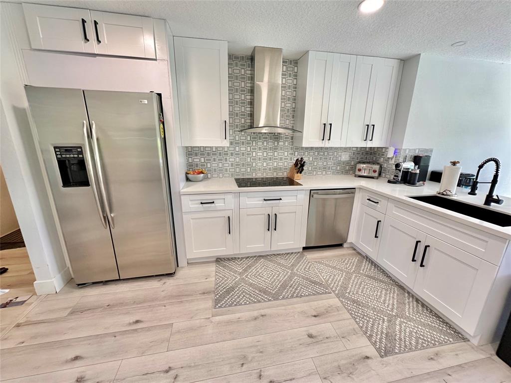 11392 Boca Woods Lane Boca Raton, FL 33428 - Photo 5 of 26 a kitchen with white cabinets a sink a stove a refrigerator and island