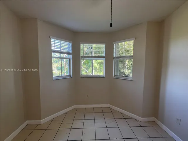 a view of a refrigerator in kitchen and an empty room