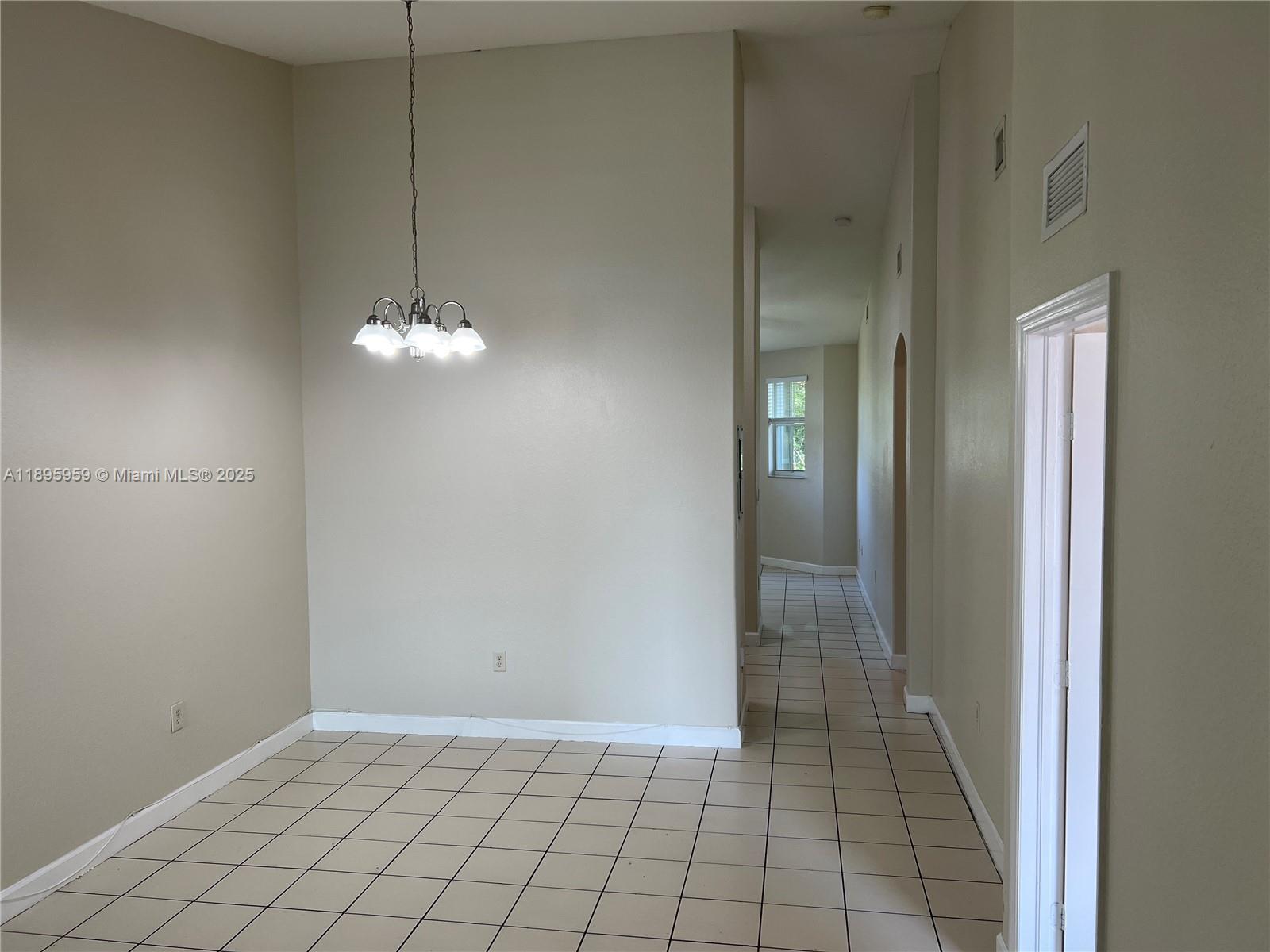 2903 Southeast 17th Avenue, Unit 201 Homestead, FL 33035 - Photo 2 of 42 an empty room with chandelier fan and kitchen view