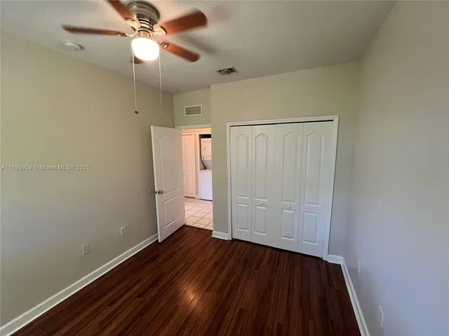 an empty room with wooden floor and fan