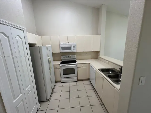 a kitchen with white cabinets a sink and appliances