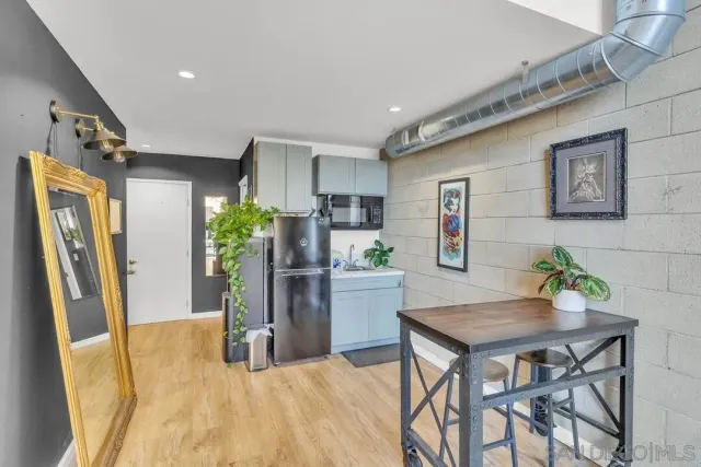 a kitchen with stainless steel appliances a dining table chairs and refrigerator