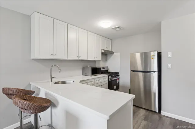 a kitchen with stainless steel appliances granite countertop a refrigerator a sink a stove a dining table and chairs