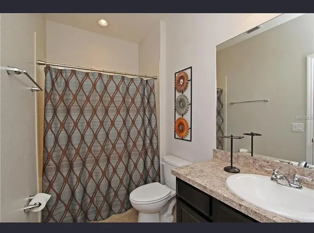 a bathroom with a granite countertop sink and a toilet