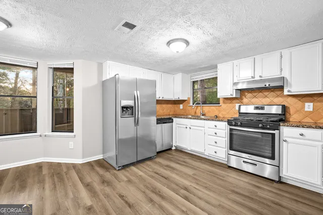 a kitchen with granite countertop a refrigerator stove and wooden floor