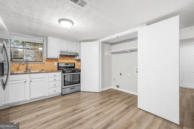 a kitchen with granite countertop a refrigerator stove and sink