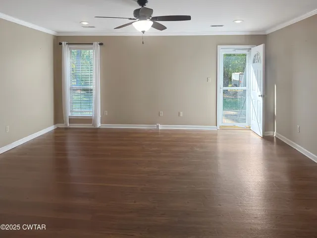 an empty room with wooden floor fan and windows