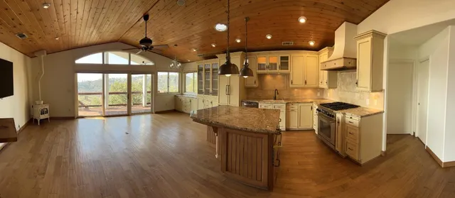 a kitchen with stainless steel appliances granite countertop a stove top oven a refrigerator a sink and dishwasher with wooden floor