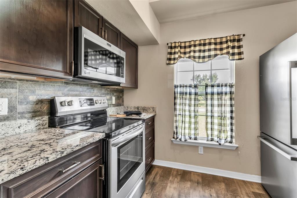 5511 Rosehill Road, Unit 203 Sarasota, FL 34233 - Photo 11 of 49 a kitchen with stainless steel appliances granite countertop a stove and a microwave