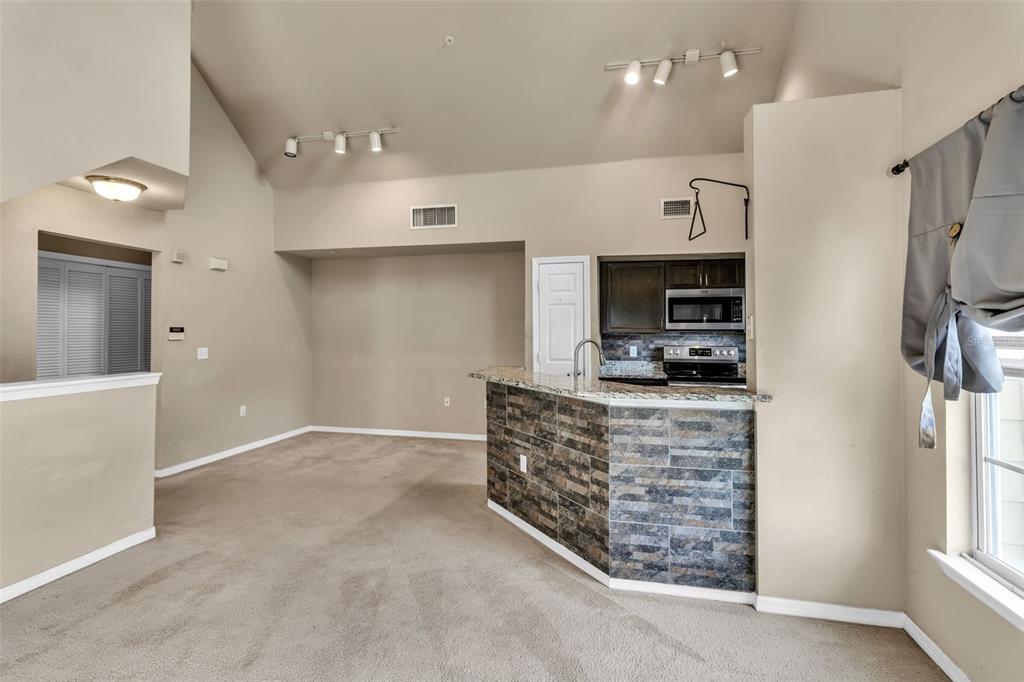 5511 Rosehill Road, Unit 203 Sarasota, FL 34233 - Photo 15 of 49 a kitchen with stainless steel appliances kitchen island granite countertop a refrigerator and a stove top oven