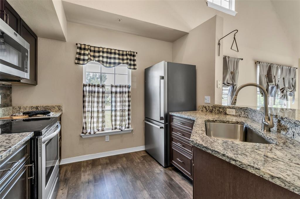 5511 Rosehill Road, Unit 203 Sarasota, FL 34233 - Photo 10 of 49 a kitchen with stainless steel appliances granite countertop a refrigerator sink and stove