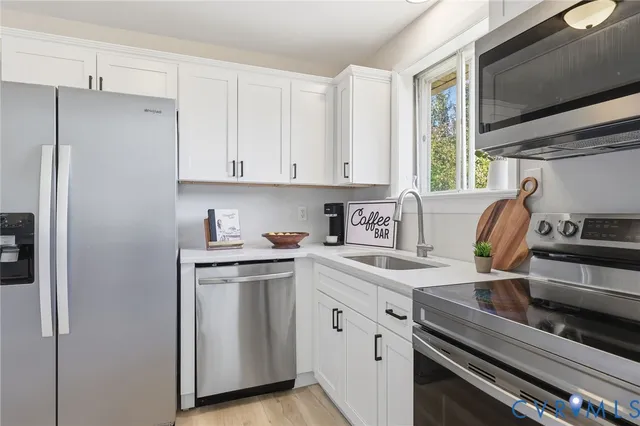 a kitchen with stainless steel appliances white cabinets and a stove top oven