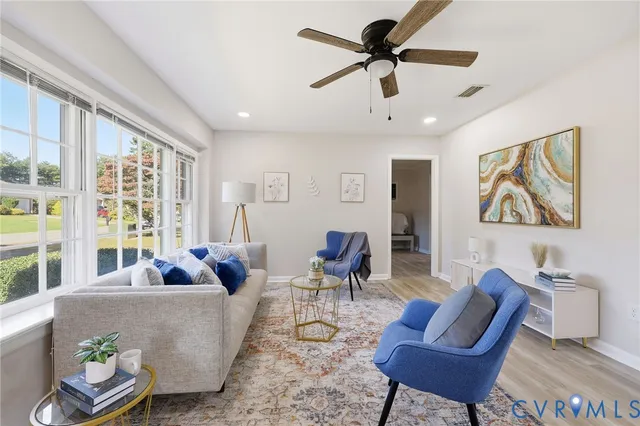 a living room with furniture a ceiling fan and a large window