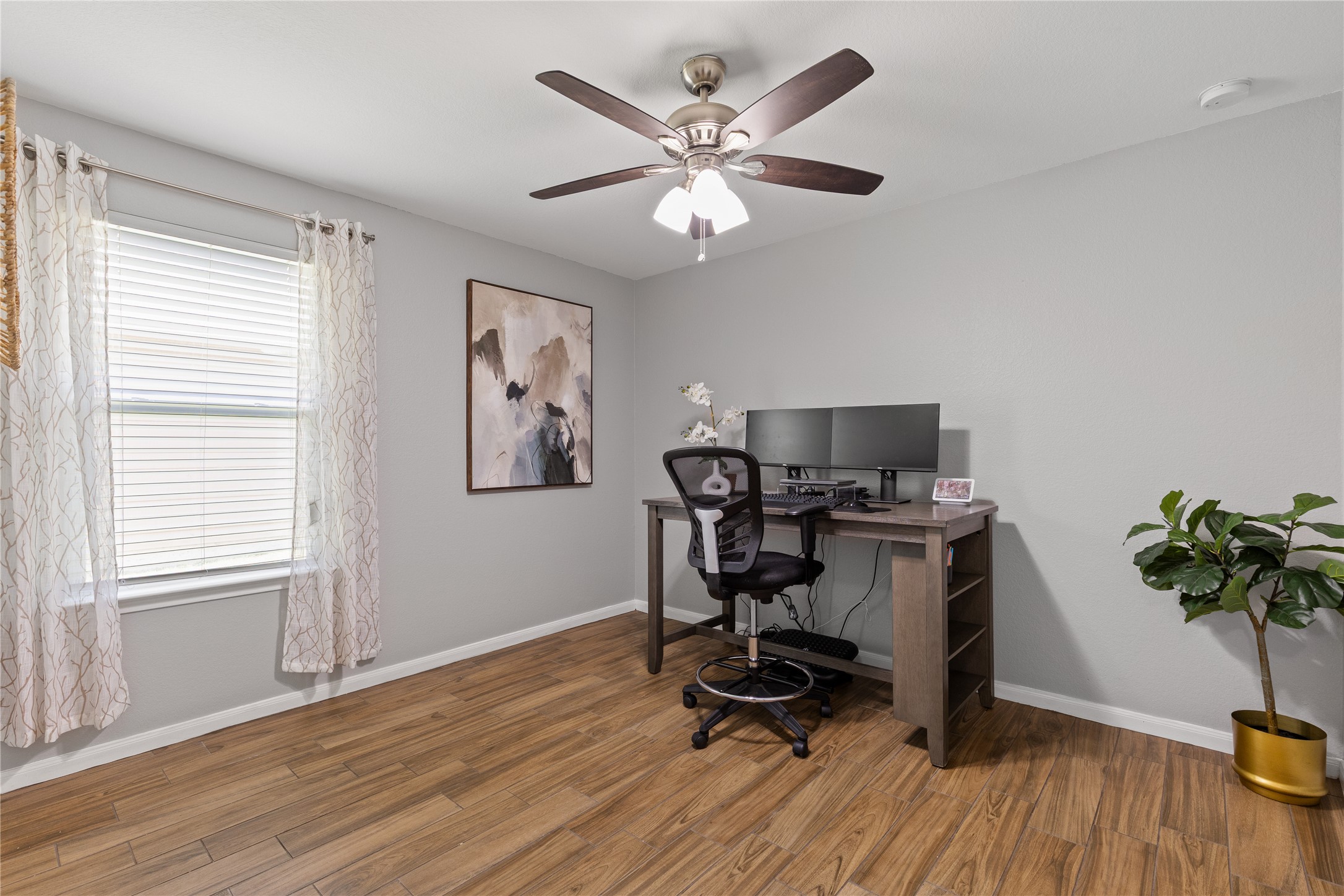 256 Alpha Kyle, TX 78640 - Photo 17 of 27 Hardwood look tile floors and a ceiling fan create a comfortable and inviting home office space.