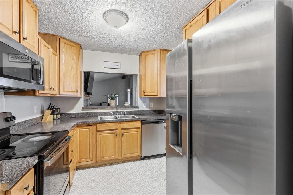 1312 Hackamore Street Mesquite, TX 75149 - Photo 8 of 23 Kitchen with stainless steel appliances, a textured ceiling, light flooring, and light wood finish cabinetry