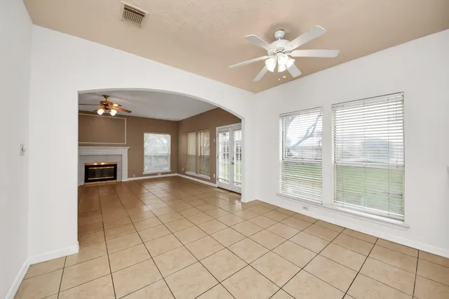 a view of an empty room with chandelier fan and fire place