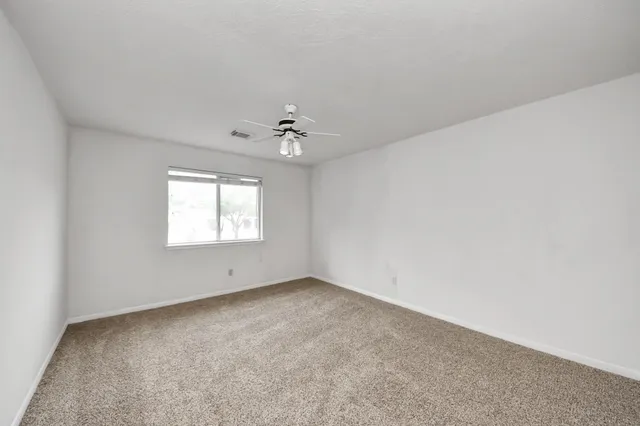an empty room with a chandelier fan and windows