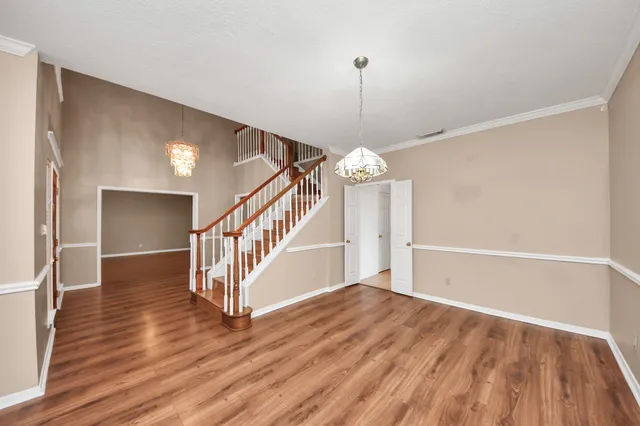 a view of an empty room with wooden floor and stairs