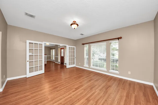 a view of an empty room with wooden floor and a window