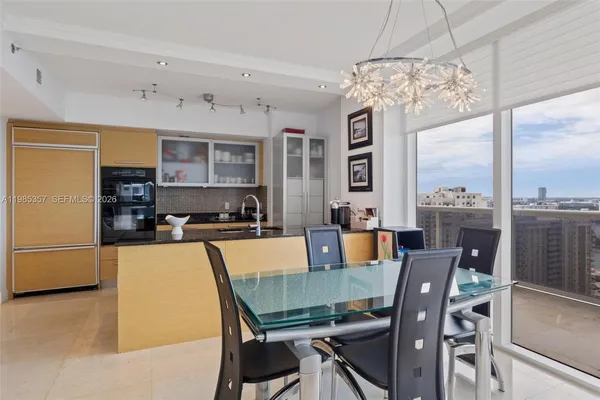 a view of a dining room with furniture a chandelier and large window