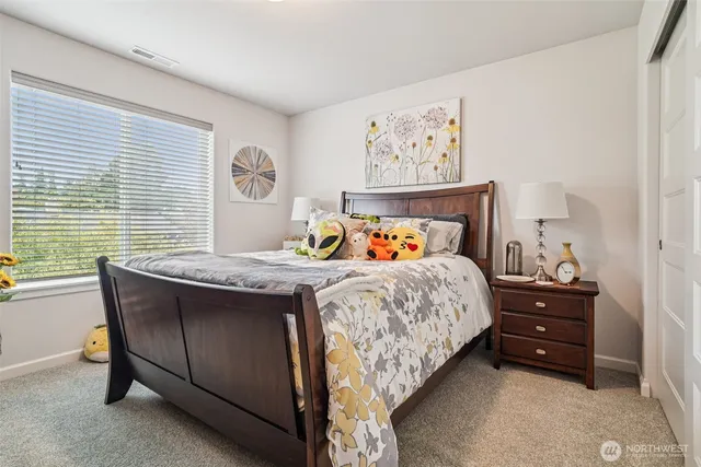 a bed sitting in a bedroom next to a window and a computer on a dresser