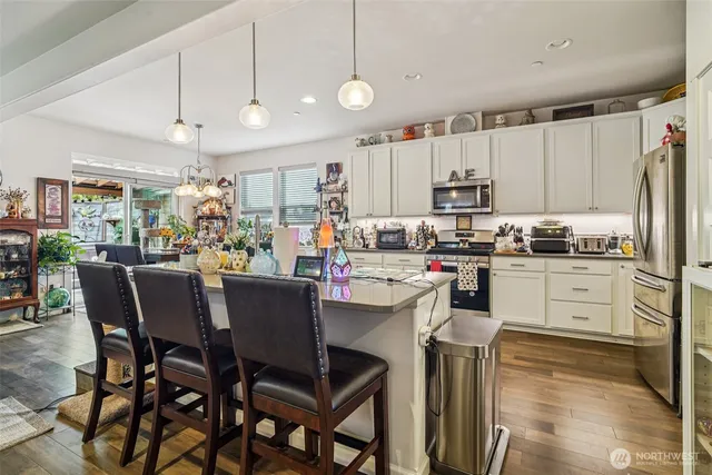 a kitchen with kitchen island a white counter top space a sink stainless steel appliances and cabinets