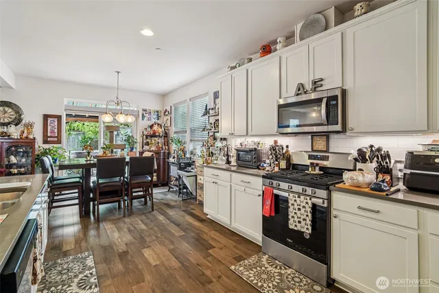 a kitchen with stainless steel appliances a stove a sink cabinets and a dining table