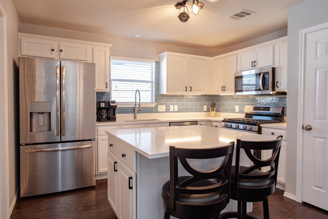 1519 Davis Mountain Loop Cedar Park, TX 78613 - Photo 10 of 39 a kitchen with stainless steel appliances granite countertop a dining table chairs refrigerator and microwave