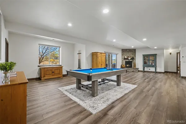 a room with wooden floor pool table and windows
