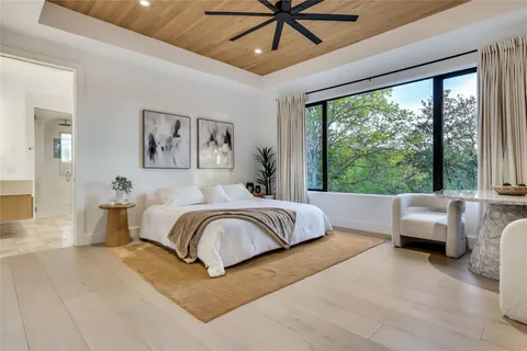 a spacious bedroom with a large bed couch and two large window