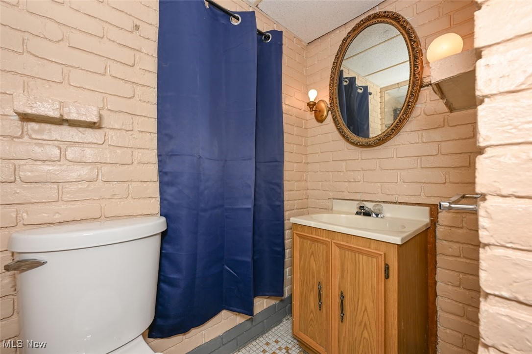 667 Elma Street Akron, OH 44310 - Photo 39 of 42 Full bathroom featuring brick wall, a stall shower, vanity, and light tile patterned floors