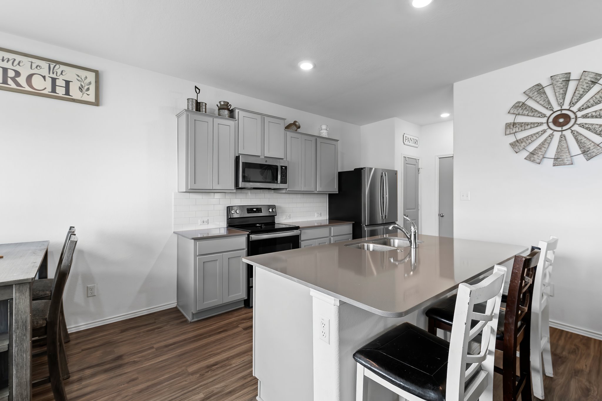 576 Greatest Gift Way Jarrell, TX 76537 - Photo 11 of 37 A contemporary kitchen features sleek gray cabinetry, stainless steel appliances, and a central island with a sink.