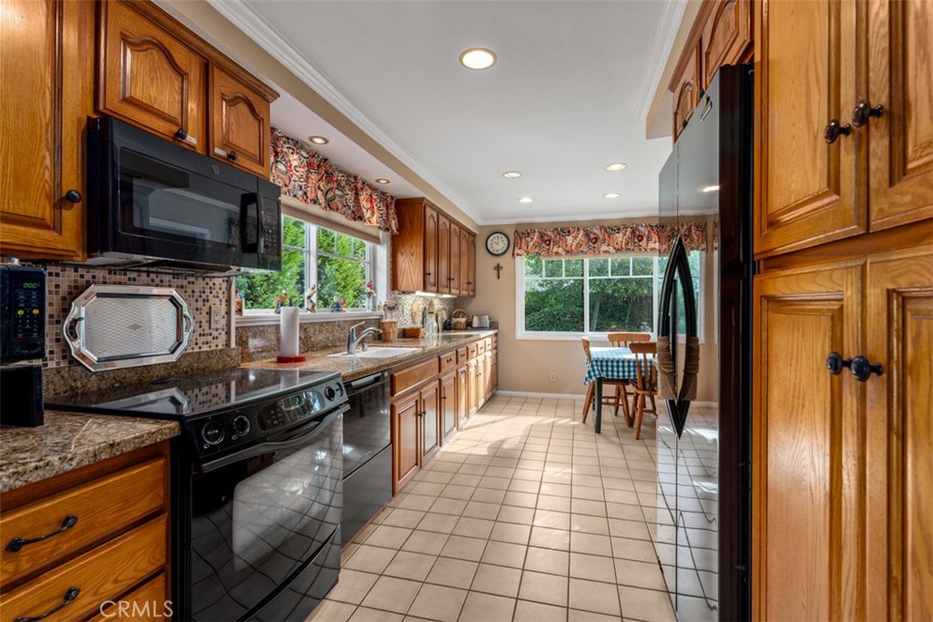 19512 Sierra Mia Road Irvine, CA 92603 - Photo 14 of 46 a kitchen with stainless steel appliances granite countertop a stove top oven a sink a dining table and chairs with the front door