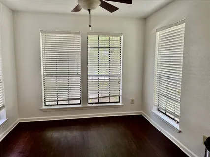 a view of an empty room with a window and wooden floor