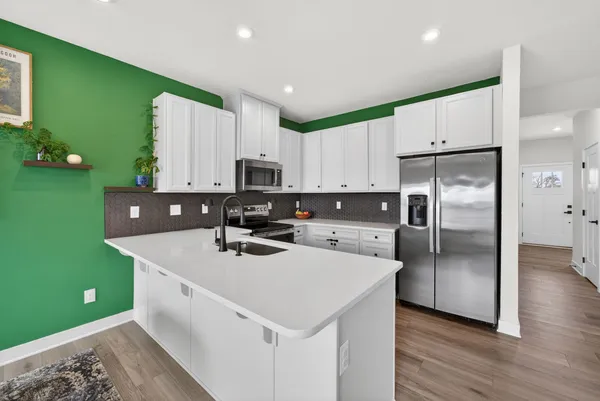 a living room with stainless steel appliances furniture a flat screen tv and a kitchen