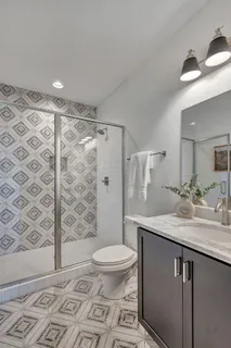 a bathroom with a granite countertop sink a toilet a mirror and shower
